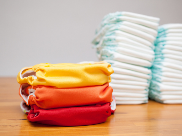 stack of cloth diapers in front of disposable diapers on table